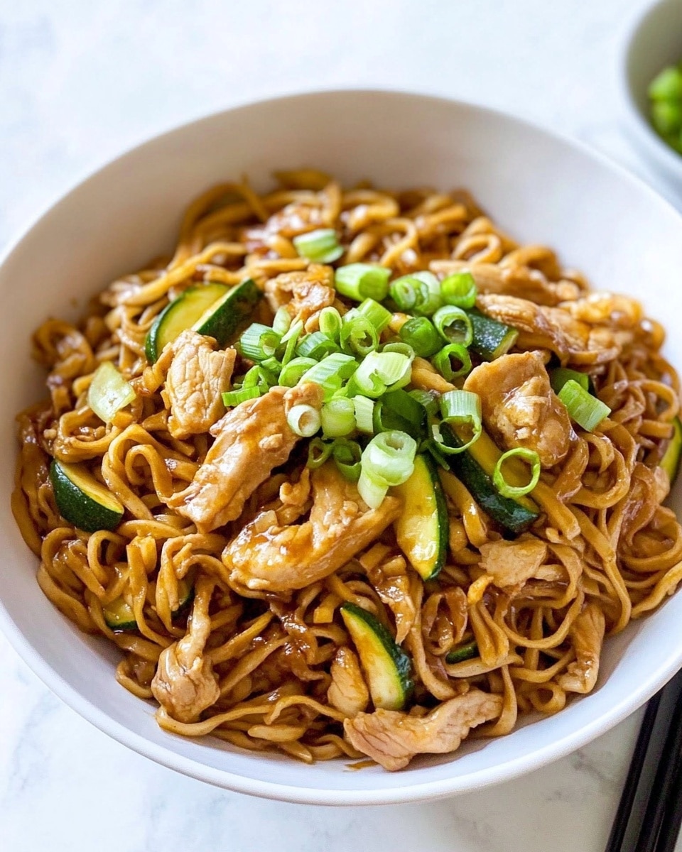 A white speckled bowl holds a serving of cooked wavy noodles mixed with light brown cooked pieces of chicken and thin slices of green vegetables, all garnished with chopped bright green spring onions scattered on top. Dark brown wooden chopsticks rest on the right edge of the bowl. Above the bowl, a small clear glass bowl contains sliced green onions, and to its right, a clear glass bowl filled with amber-colored sauce with red chili flakes has a silver spoon resting inside. The bowls and cloth with a red stripe are placed on a white marbled surface. photo taken with an iphone --ar 4:5 --v 6.1