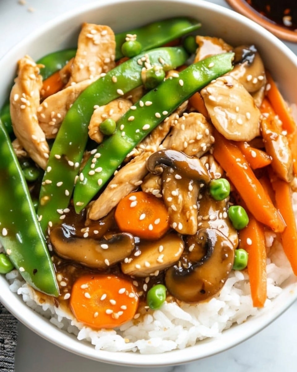 A white bowl filled with three layers: the bottom layer is white rice with a soft texture, the middle layer consists of bright green snow peas and dark brown mushrooms sliced thinly, and the top layer has light brown cooked chicken pieces, orange carrot slices, and light beige bamboo shoots, all covered with a shiny brown sauce and sprinkled with small sesame seeds. A pair of wooden chopsticks rest on the edge of the bowl, which sits on a white marbled surface. In the background, a blurred white bowl with more of the same dish is visible. Photo taken with an iphone --ar 4:5 --v 6.1