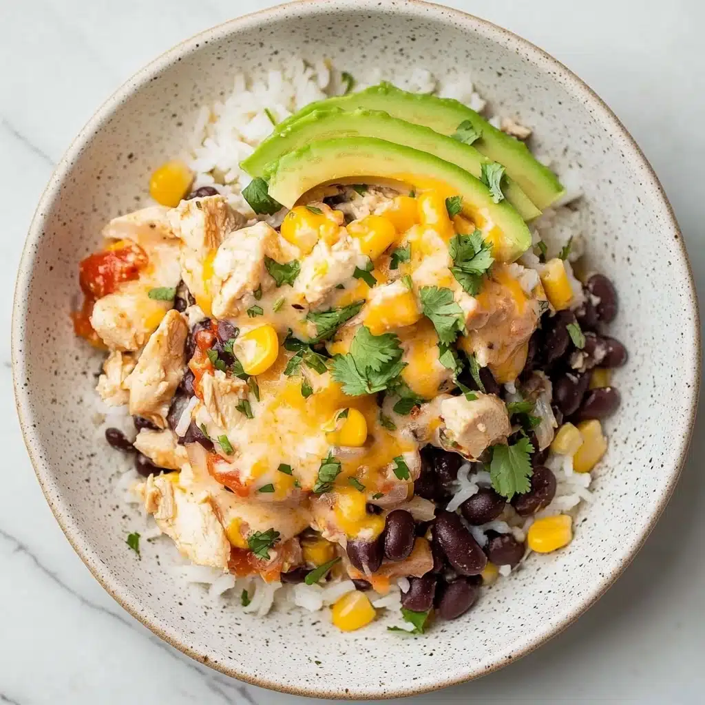 The image shows a white rectangular baking dish filled with a layered casserole. The bottom layer looks creamy, topped with scattered black beans and bright yellow corn kernels mixed with bits of red tomatoes. Over this, there is a melted cheese layer that looks golden and bubbly in places. Two sets of sliced green avocado fan over the corners of the dish. Small bits of green herbs are sprinkled on top and around the dish. The dish sits on a white marbled surface with some scattered green herbs and a blue and white checkered cloth next to it. Photo taken with an iphone--v 6.1