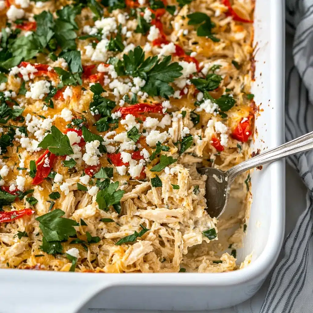 A close-up view of a white rectangular casserole dish filled with a baked pasta dish that has three visible layers: a bottom layer of cooked leafy greens mixed with small pieces of white chicken, a middle layer of creamy light orange sauce mixed with bow-tie pasta, roasted red pepper pieces, and scattered green herbs, and a top layer sprinkled with crumbled white cheese and more fresh green parsley leaves. A metal serving spoon is stuck into the dish on the right side. The dish is placed on a white marbled surface with a small white plate holding green parsley visible at the bottom right corner. Photo taken with an iphone--v 6.1