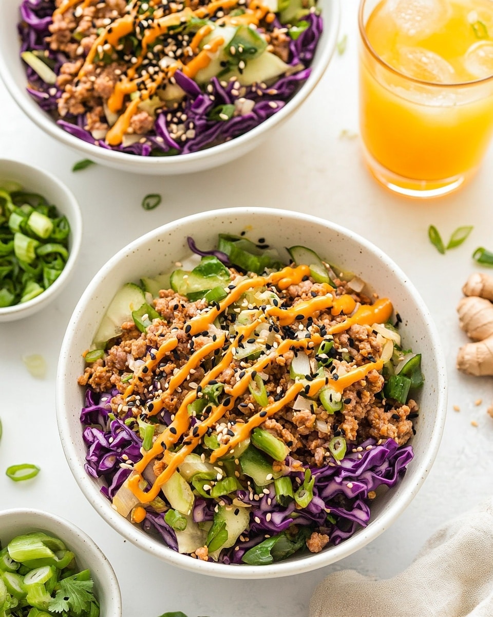 Two white bowls filled with a layered salad sit on a white marbled surface. Each bowl holds a mix of colorful shredded cabbage, with deep purple and light green pieces, and bits of cooked ground meat scattered throughout. Orange sauce is drizzled across the top of each bowl in thin lines, sprinkled with small black sesame seeds and small green onion slices. Around the bowls, there are pieces of fresh ginger root, a small bowl of chopped green onions, and two clear glasses with a light yellow drink. photo taken with an iphone --ar 4:5 --v 6.1