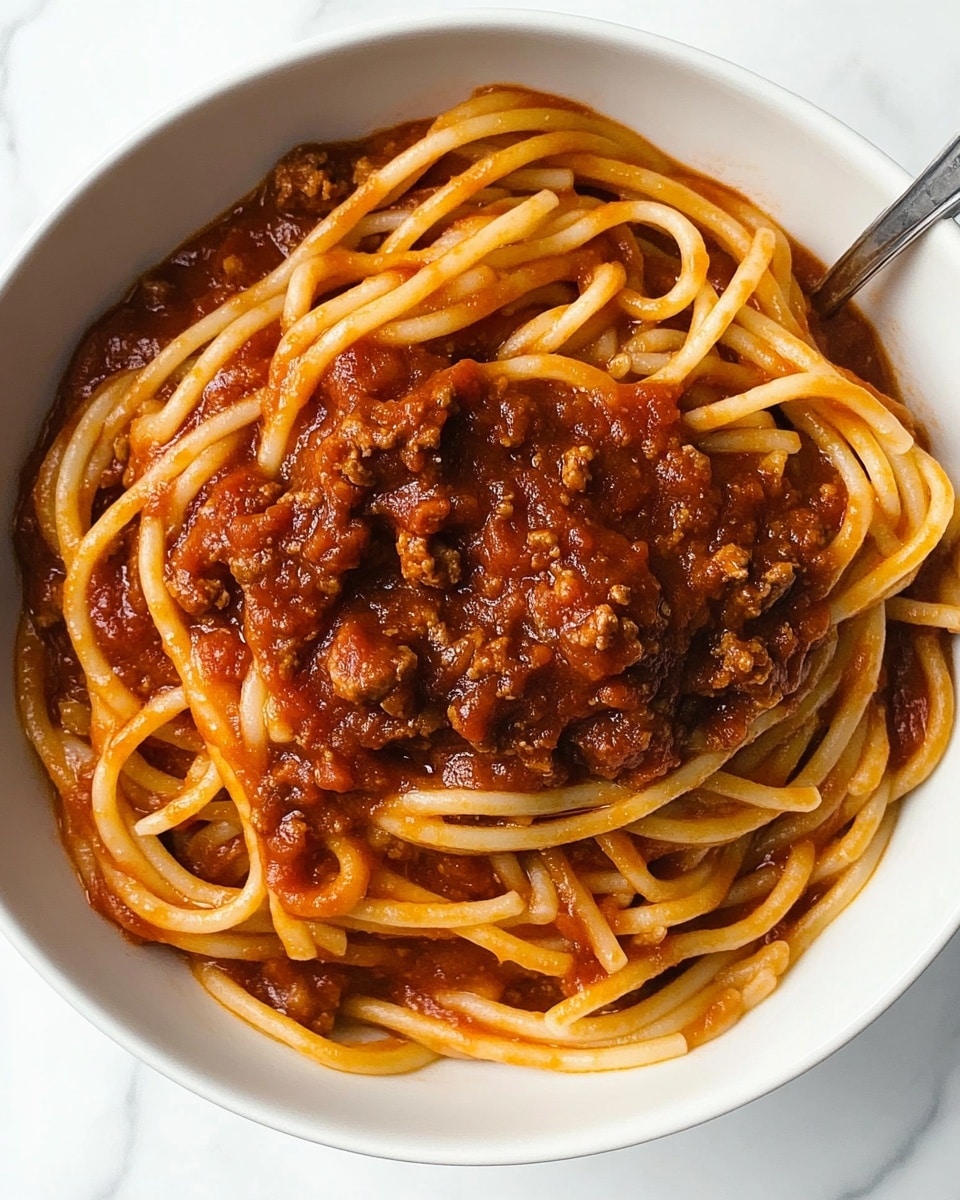 The image shows a thick, rich tomato sauce inside a white pot with a black rim. The sauce is a deep red color with small bits of herbs and spices visible throughout, giving a slightly textured look. A white spoon is partially scooping the sauce from the pot, showing the sauce's smooth yet chunky consistency. The pot is set on a white marbled surface. photo taken with an iphone --ar 4:5 --v 6.1