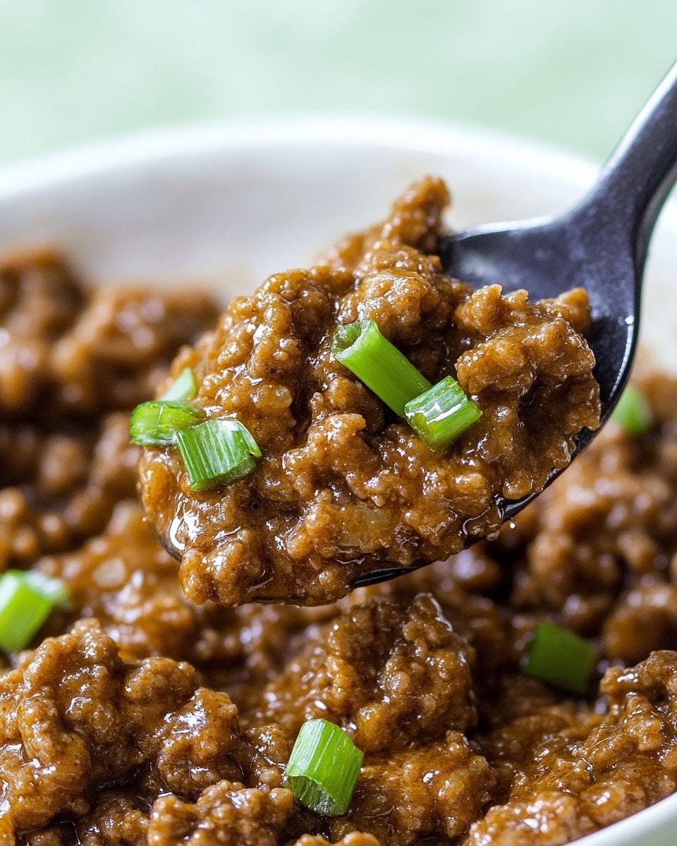 A close-up view shows a spoon holding a thick, brown cooked ground meat mixture with a glossy texture. The ground meat has small pieces of green onion scattered inside, adding a pop of green color. The spoon is above a white bowl filled with the same meat mixture, with visible green onion pieces mixed throughout. The background is a soft light green color. The whole scene is on a white marbled surface. photo taken with an iphone --ar 4:5 --v 6.1