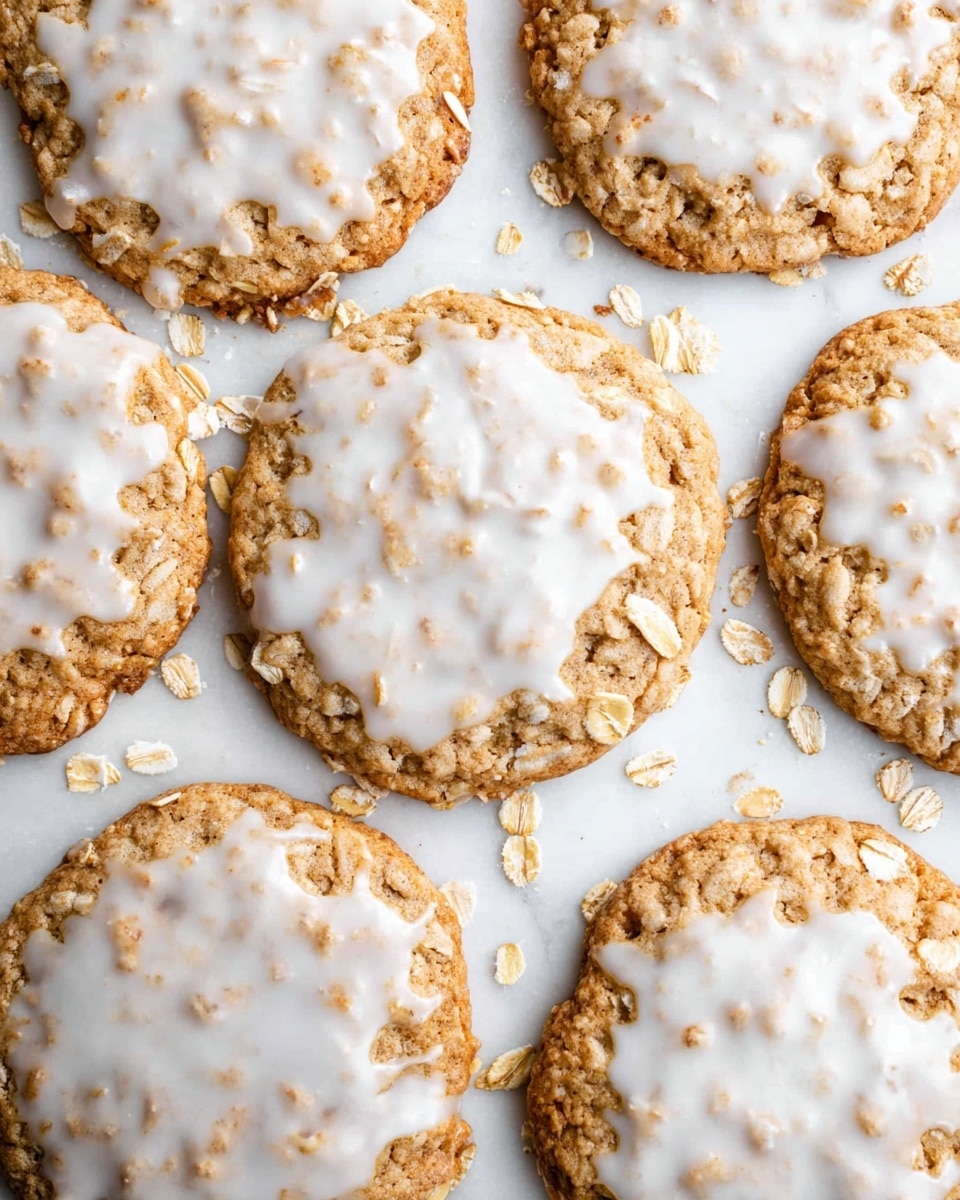 A close-up of several oatmeal cookies stacked and spread on a gold cooling rack over a white marbled surface. Each cookie is round, light brown with visible oats, and topped with a thin layer of uneven white icing drizzled across the tops. The cookies show a rough, textured surface from the oats beneath the smooth glossy icing. There is a blue and white checkered cloth partially underneath the cooling rack. Photo taken with an iphone --ar 4:5 --v 7