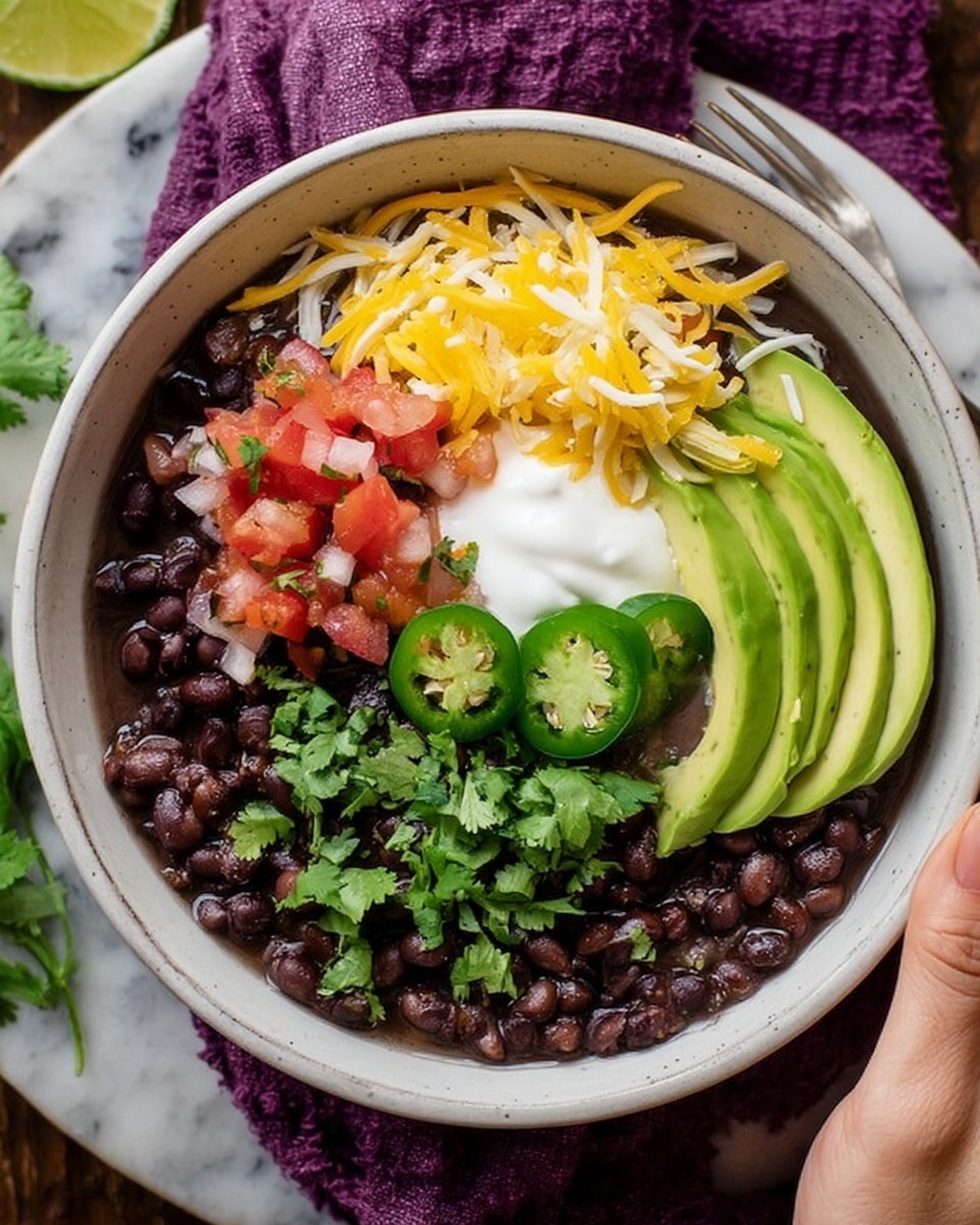 A bowl filled with dark black beans forms the base layer, topped with a small dollop of white sour cream in the center, bright yellow shredded cheese on one side, and a mix of red diced tomatoes with green chopped onions and jalapeño slices near the top. On the right, there are three smooth slices of light green avocado layered neatly. Fresh green cilantro leaves are scattered across the top for garnish. A woman's hand is holding the bowl on the left side, and another woman's hand is holding a spoon dipping into the beans on the right. The bowl is white and placed on a white marbled surface with a purple cloth underneath. Photo taken with an iphone --ar 4:5 --v 7