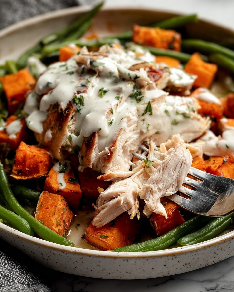 A white bowl holds a layered dish starting with a base of roasted orange sweet potato cubes and bright green beans mixed with browned bacon pieces, topped with two pieces of cooked light golden chicken. The chicken has a drizzle of white creamy sauce with small green herb flakes. Fresh green herb sprigs are placed on top. A silver fork rests inside the bowl on the left side. The bowl sits on a white marbled surface with a small bowl of white sauce with pepper and a spoon, a small bowl of crushed black pepper, some green herb sprigs, and a striped cloth napkin with a silver knife and fork nearby. photo taken with an iphone --ar 4:5 --v 7