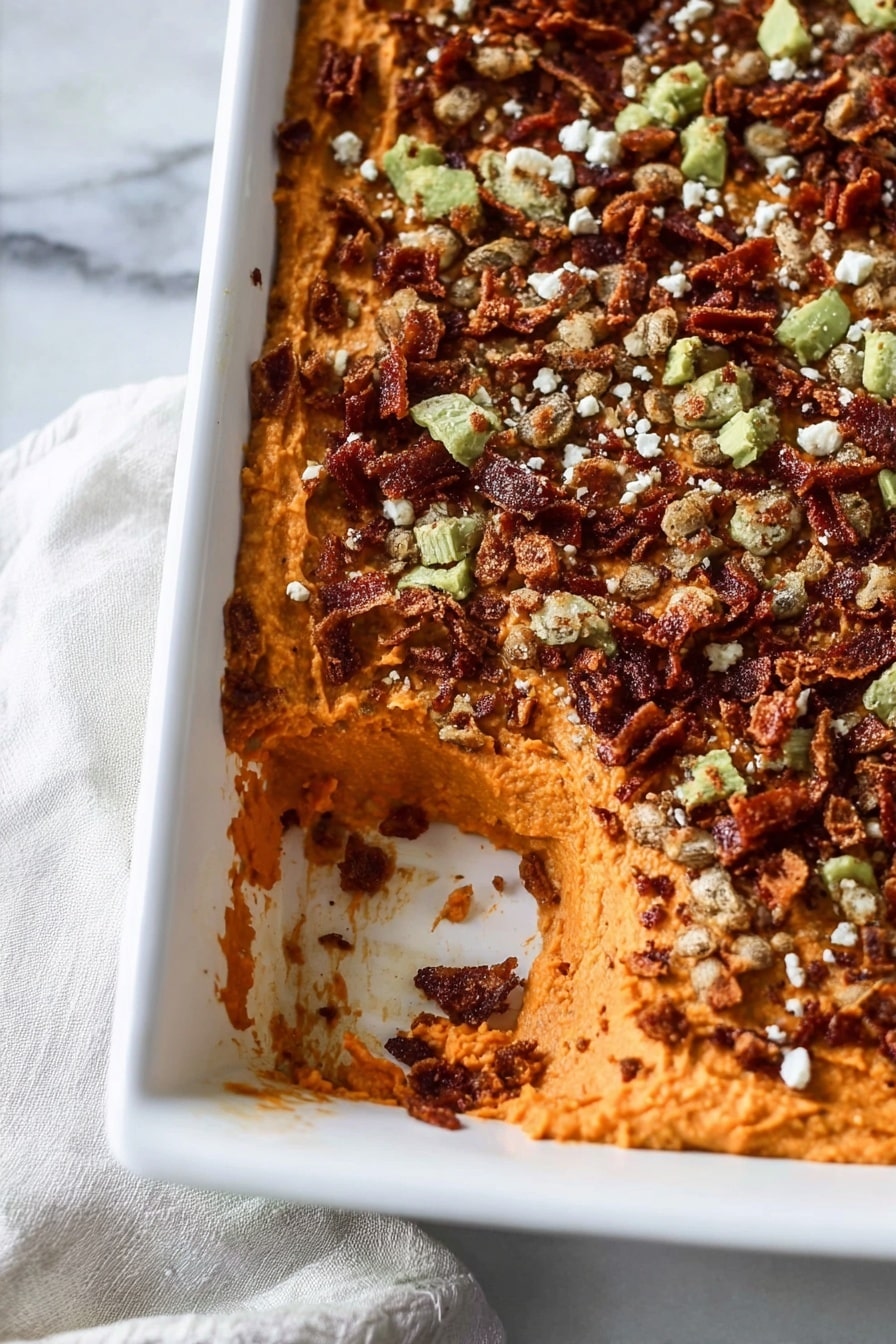 This image shows a white rectangular dish filled with a layered dip. The bottom layer is a smooth, orange color, likely a mashed ingredient with a soft texture. The top layer is covered with a dark reddish-brown mixture scattered with crispy small pieces of green and brown, possibly fried, along with small white crumbles sprinkled all over. Part of the dish has been scooped out from one corner, revealing the thick orange layer underneath. The dish is placed on a white marbled surface with a light cloth partially visible underneath. Photo taken with an iphone --ar 2:3 --v 7 - Savory Sweet Potato Casserole with Bacon, Caramelized Shallots, and Crispy Jalapeños, sweet potato casserole with bacon and jalapeños, gourmet sweet potato bake, savory sweet potato side dish, spicy bacon sweet potato recipe