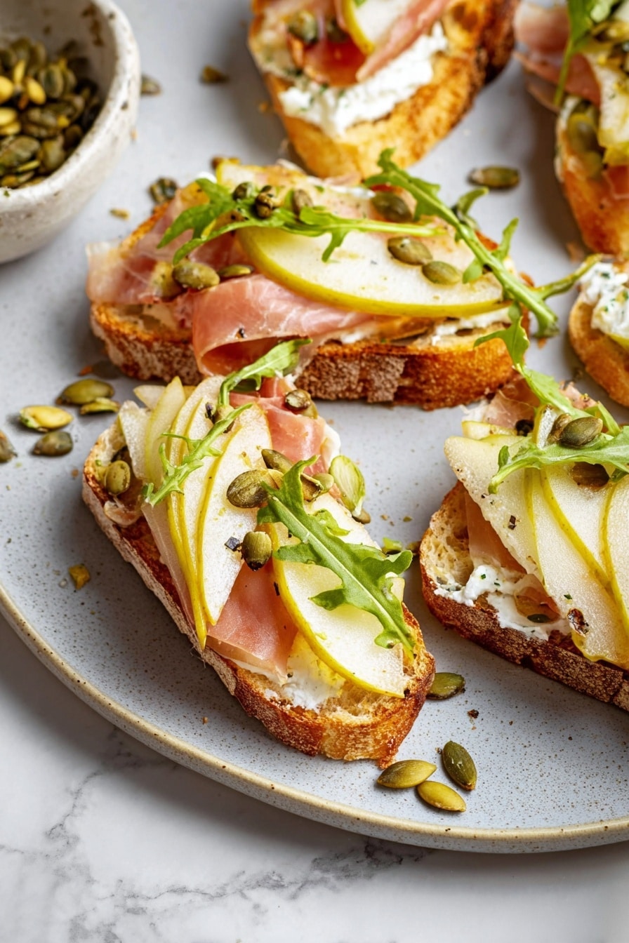 The image shows slices of toasted bread topped with a layer of white creamy spread, thin folded slices of pink ham, and a slice of pear with its reddish skin. On top of these, there is a small pile of mixed green and brown nuts and seeds, along with some fresh green leaves scattered over the top. The bread has a golden-brown crispy crust with a soft texture inside. The toasts are arranged on a white plate placed on a white marbled surface, with a few loose leaves and nuts around the plate. photo taken with an iphone --ar 2:3 --v 7 - Ricotta and Pear Crostini with Salty Pumpkin Seed Pistachio Crunch, pear crostini with ricotta, gourmet appetizer with pear and nut crunch, easy pear and ricotta crostini, sophisticated appetizer for entertaining