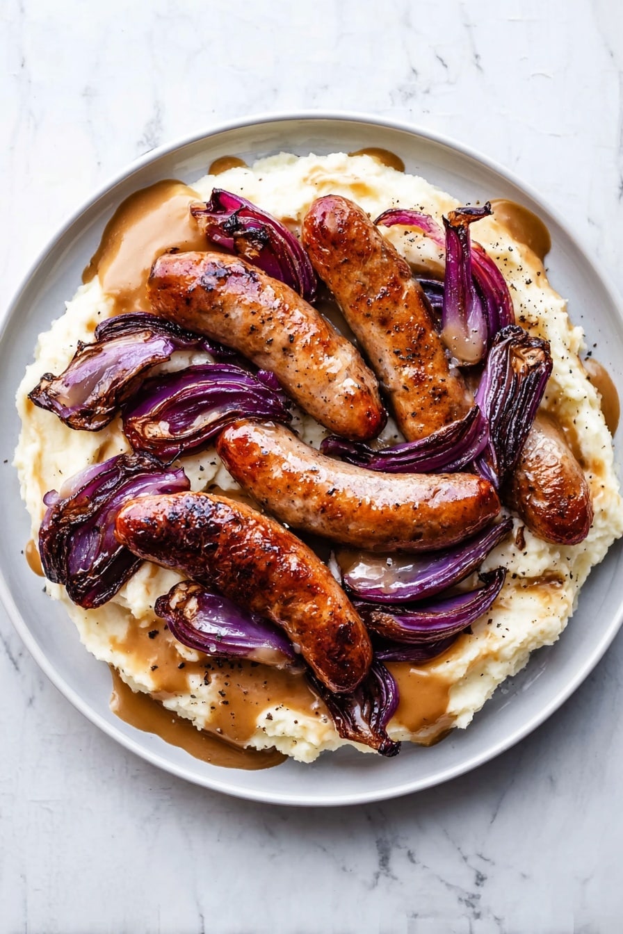 The dish is served on a white plate with a base layer of creamy, smooth mashed potatoes in a pale off-white color. On top of this, several browned sausages with a shiny, slightly crispy skin are laid arranged close together. Scattered among the sausages are slices of roasted red onion, showing a deep purple color with slightly blackened, caramelized edges. A light brown gravy covers part of the mashed potatoes and sausages, with a slightly glossy texture and small specks of black pepper visible on the surface. The plate is set on a white marbled surface. photo taken with an iphone --ar 2:3 --v 7 - Bangers and Mash with Caramelized Onions, British comfort food recipes, hearty sausage and mash dish, easy traditional British dinner, caramelized onion recipes