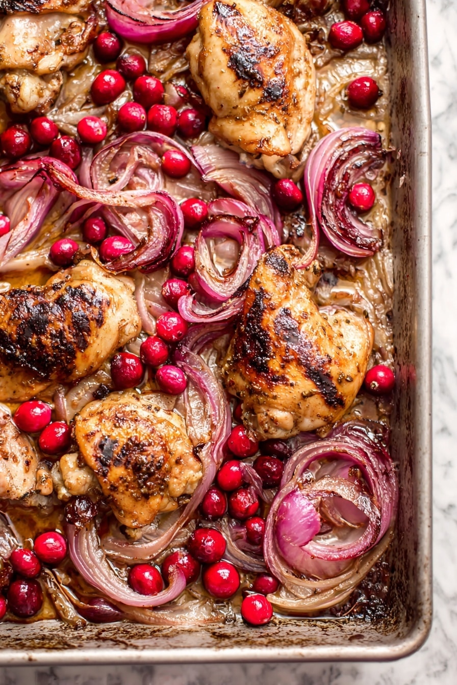 A white plate with two stacked pieces of browned cooked meat as the base layer, topped with shiny cooked red onion slices and bright red cranberries scattered on and around the meat. To the right side of the meat is a generous serving of creamy mashed potatoes with some cranberries mixed in and on top. A small green herb garnish rests on the onions. A fork is placed on the right edge of the plate. The plate sits on a white marbled surface. Photo taken with an iphone --ar 2:3 --v 7 - Roasted Balsamic Chicken with Cranberries, balsamic chicken recipes, easy holiday chicken, flavorful chicken dinner, cranberry chicken skillet