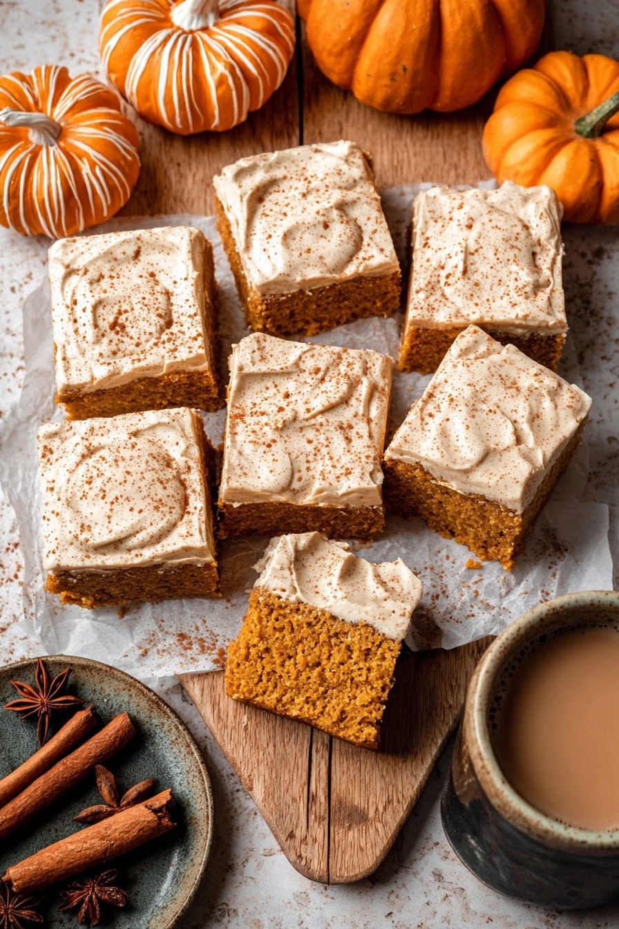 The image shows a close-up of a square piece of moist pumpkin cake with two layers: the bottom layer is a soft, spongy pumpkin-colored cake with visible crumbs, and the top layer is a thick, creamy light brown frosting sprinkled with a fine dust of cinnamon. Behind this piece, there are several similar square pieces arranged closely together, all frosted on top with the same cinnamon sprinkled frosting. The cake squares sit on a light brown parchment paper over a wooden surface, with star anise spices positioned near the front edges of the cake pieces. The blurred background shows a muted orange pumpkin and a matching vase, all against a white marbled texture surface. photo taken with an iphone --ar 2:3 --v 7 - Pumpkin Spice Latte Cake with Espresso Cream Cheese Frosting, pumpkin spice cake, fall desserts, pumpkin latte dessert, espresso frosting cake