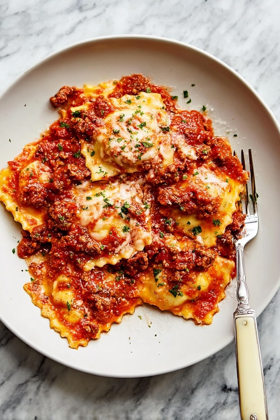 The image shows a black oval baking dish filled with baked ravioli layered in tomato sauce with melted, bubbly cheese on top. The ravioli are round with crimped edges, covered with thick, rich red tomato sauce mixed with some bits of meat. The cheese is golden and slightly browned in spots, melted evenly across the whole dish. Small green parsley flakes are sprinkled over the cheese for color. A silver spoon scoops out a portion from the middle, showing the soft, saucy ravioli inside. The dish sits on a white marbled surface next to a small white bowl of chopped parsley and a gray checked cloth. Photo taken with an iphone --ar 2:3 --v 7 - Baked Ravioli with Italian Sausage and Mozzarella, Italian sausage baked pasta, cheesy ravioli bake, comforting Italian casserole, easy baked ravioli dinner