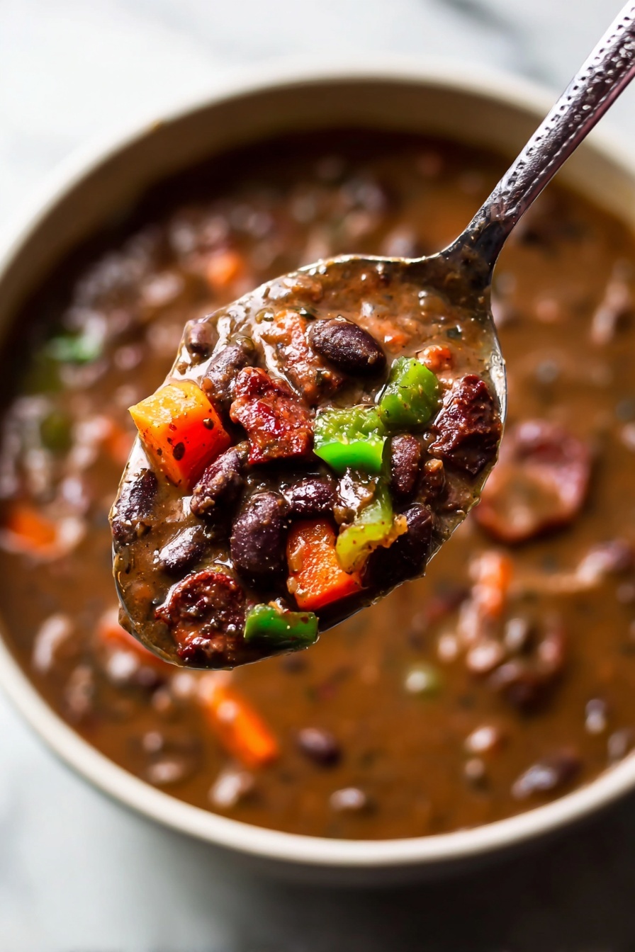 A white bowl filled with thick dark brown black bean stew, showing black beans, small pieces of green and red bell peppers, and browned slices of sausage spread across the stew. On top, there is a dollop of white sour cream with finely chopped purple and white onions sprinkled over it. Fresh green cilantro leaves are scattered around the bowl. A silver spoon rests inside on the left edge of the bowl, which sits on a white marbled surface with some green cilantro leaves nearby. photo taken with an iphone --ar 2:3 --v 7 - Black Bean Soup with Smoked Sausage and Chili Spices, hearty black bean soup recipe, smoky sausage soup, spicy bean soup, easy make-ahead soup