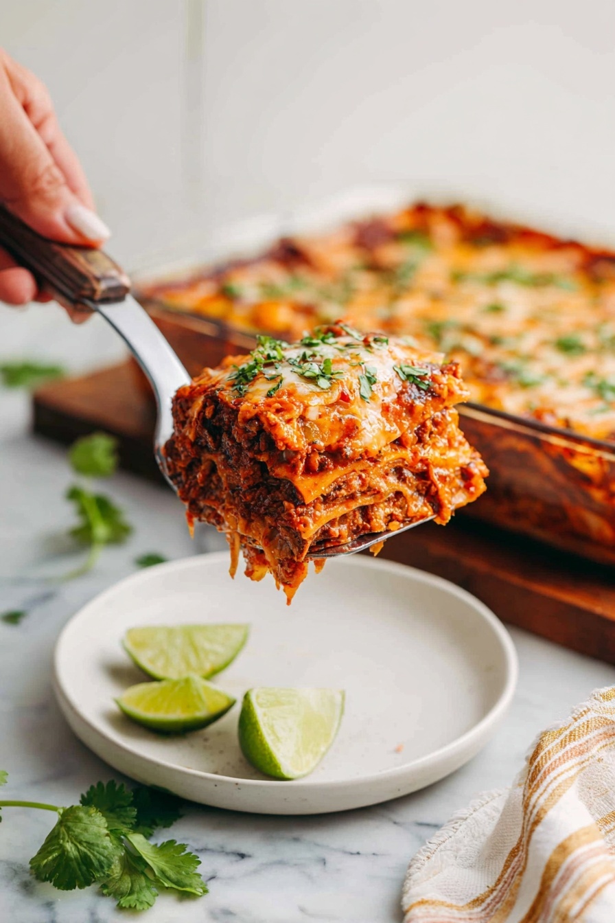A square piece of layered lasagna lifted by a utensil held by a woman's hand, showing multiple layers of reddish meat sauce, melted cheese, and pasta sheets all topped with chopped green herbs. In the background, the metal baking pan with more lasagna sits on a wooden board. Below, a white plate holds two lime wedges and is placed on a white marbled surface with some green cilantro leaves nearby and a beige striped cloth partially visible. photo taken with an iphone --ar 2:3 --v 7 - Chicken Enchilada Casserole, easy enchilada casserole, cheesy chicken casserole, Mexican-inspired casserole, weeknight dinner ideas