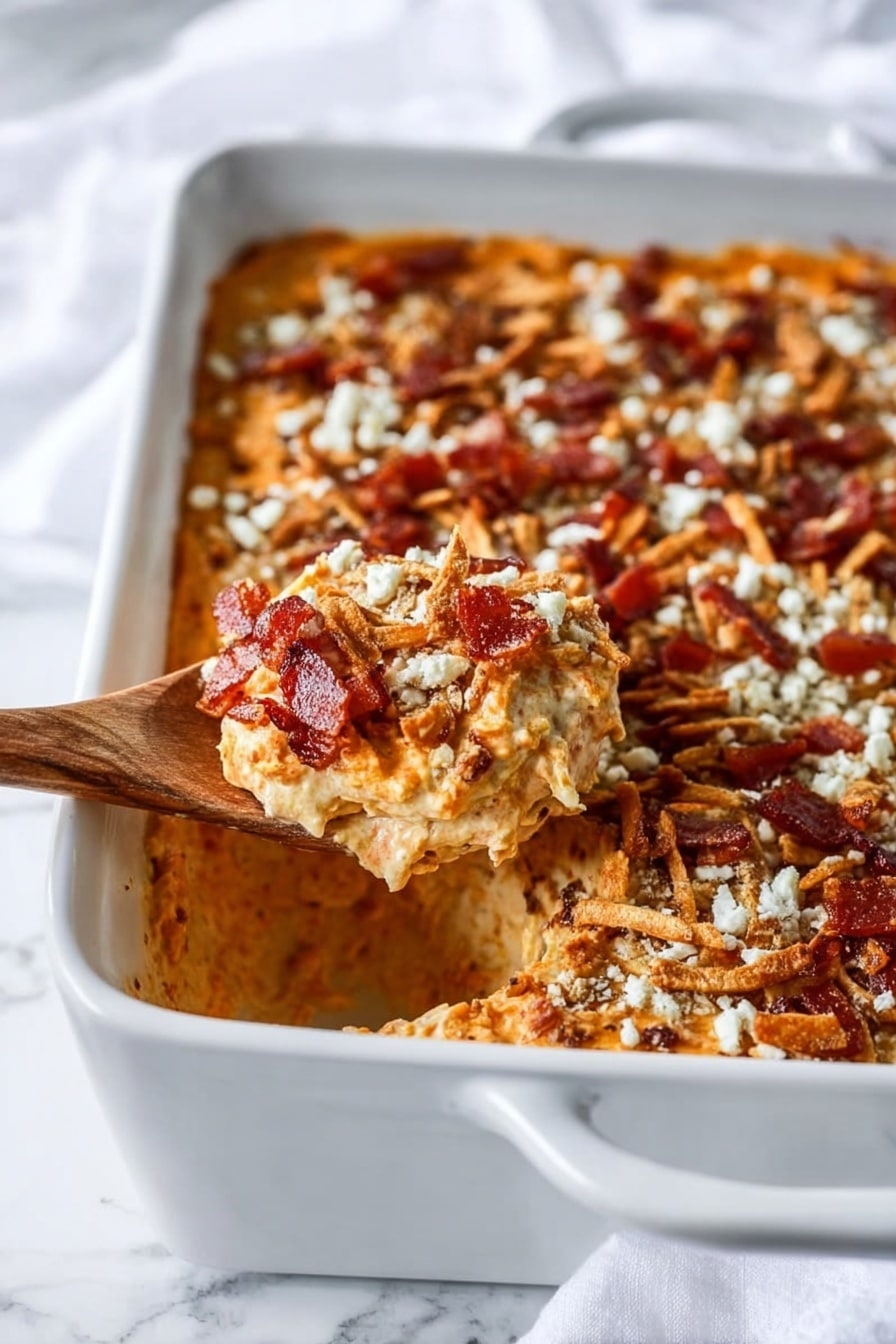 A white rectangular baking dish filled with a three-layered dip. The bottom layer is smooth and orange, likely a cheese or dip base. The middle layer is sprinkled with crispy reddish-brown bacon pieces. The top layer has light golden-brown fried onion strings and a scattering of finely grated white cheese. A wooden spoon is scooping out a portion of the dip from the corner, showing the creamy orange layer beneath the toppings. The dish is placed on a white marbled surface with a white cloth visible in the background. Photo taken with an iphone --ar 2:3 --v 7 - Savory Sweet Potato Casserole with Bacon, Caramelized Shallots, and Crispy Jalapeños, sweet potato casserole with bacon and jalapeños, gourmet sweet potato bake, savory sweet potato side dish, spicy bacon sweet potato recipe