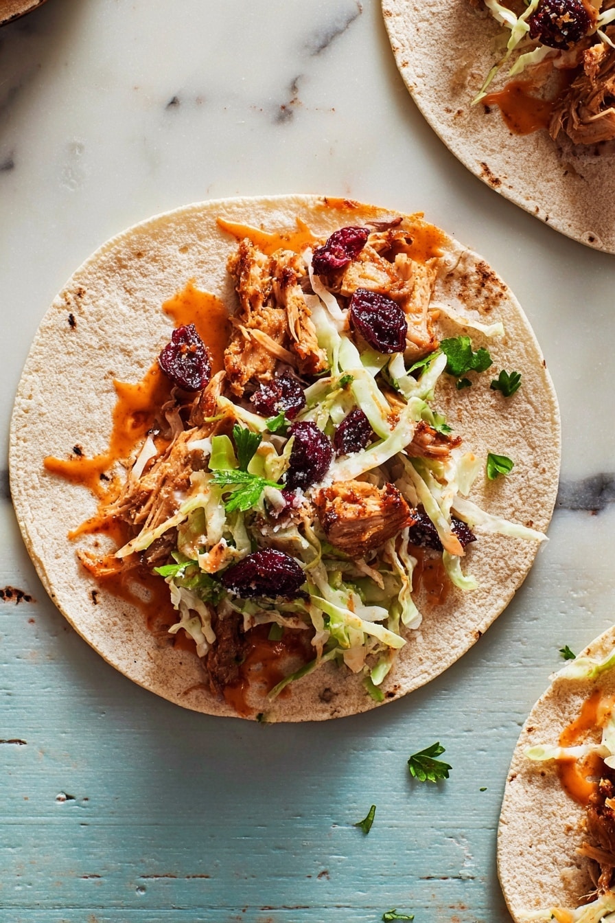 A single open tortilla taco is placed on a white marbled surface. The bottom layer is a soft, light beige tortilla. On top, there is a layer of reddish-orange sauce spread unevenly. Above the sauce, there are pieces of browned cooked meat with some caramelized edges. Shredded pale green and white cabbage is scattered over the meat layer. Small dried red berries and a few fresh green parsley leaves garnish the top. The taco is the main focus, with another partially visible tortilla holding similar filling in the top right corner. photo taken with an iphone --ar 2:3 --v 7 - Thanksgiving Leftover Tacos, leftover turkey ideas, Thanksgiving dinner ideas, easy holiday leftovers, festive taco recipes