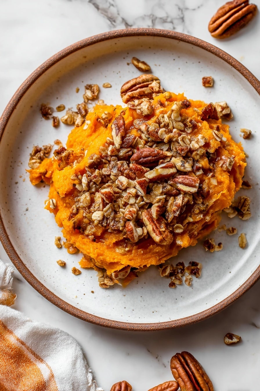 A rectangular white baking dish filled with a layered dessert. The bottom layer is a smooth, soft orange sweet potato mash, and the top layer is a crumbly oat and nut mixture that looks toasted and crunchy, covering the mash unevenly. There are visible whole pecan pieces mixed with the oats, giving it a rough texture. A spoon is scooping from the dish, showing both layers clearly. The dish rests on a white marbled surface with a white and orange cloth nearby. photo taken with an iphone --ar 2:3 --v 7 - Sweet Potato Casserole with Pecans and Toasted Oat Topping, sweet potato casserole with pecans, best sweet potato casserole, holiday sweet potato dish, easy sweet potato casserole