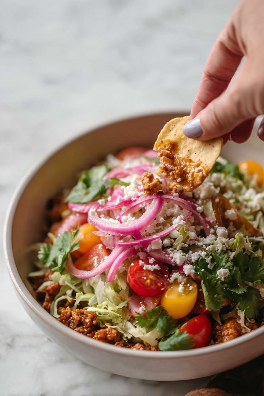 A pink pan filled with layers starting with a cooked crumbly brown base, topped with small golden round chips arranged around the edge, followed by a mix of chopped red and yellow cherry tomatoes, shredded pale green lettuce, and chopped green herbs. On top of this, there are thin slices of purple onion and a dollop of bright green guacamole in the center, garnished with white crumbled cheese and a wedge of lime placed near the middle. The pan sits on a white marbled surface scattered with lime wedges and a few of the same golden chips. Photo taken with an iphone --ar 2:3 --v 7 - Turkey Taco Skillet, quick turkey taco dinner, healthy taco skillet, one-pan turkey taco recipe, easy turkey taco meal