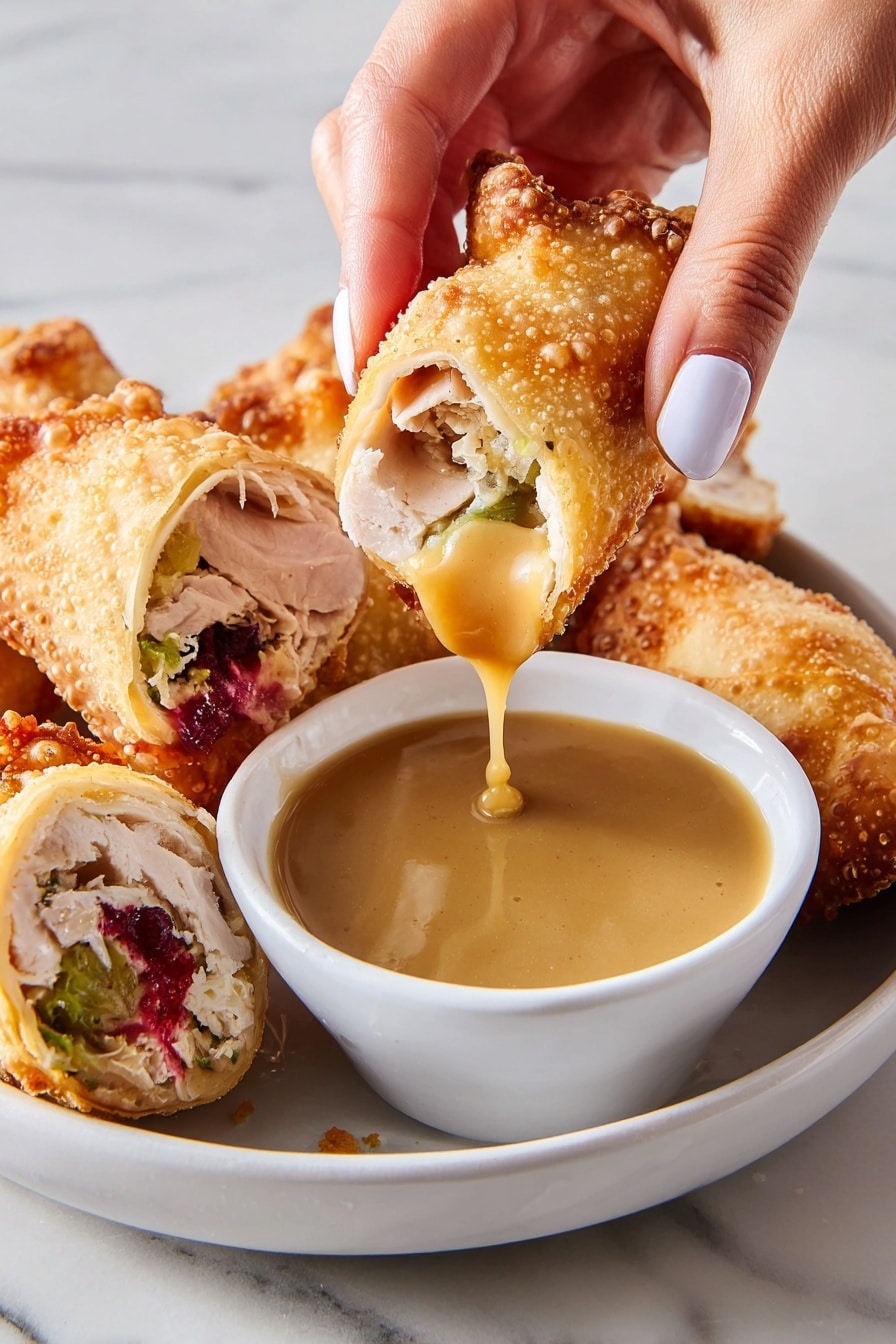A close-up of a golden brown crispy roll being held by a woman's hand with light blue nail polish, dipped into a small white bowl filled with smooth light brown gravy, with some gravy dripping back into the bowl; on a white plate with several more crispy rolls, one cut in half showing layers inside including light pink meat, green stuffing, white cheese, and bright red sauce oozing out, all on a white marbled surface. photo taken with an iphone --ar 2:3 --v 7 - Thanksgiving Leftover Egg Rolls, leftover turkey egg rolls, crispy turkey leftover snacks, holiday leftover appetizers, easy Thanksgiving leftover recipes