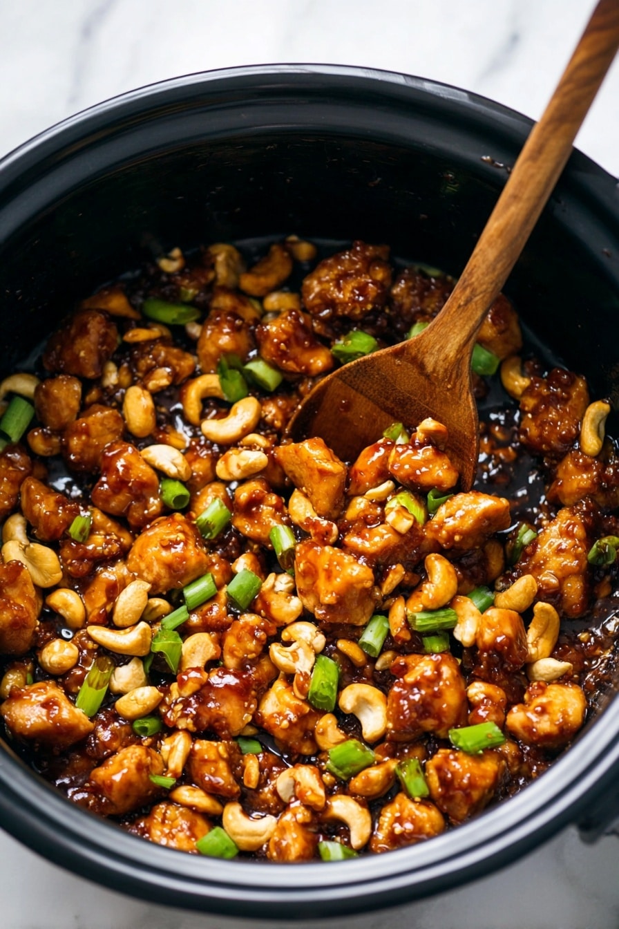 A black pot filled with many small, golden brown pieces of chicken coated in a glossy, dark brown sauce mixed with light brown cashew nuts and bright green sliced scallions, showing a rich and savory texture. A wooden spoon is scooping some of the chicken and nuts from the pot, with pieces looking tender and slightly crispy on the edges. The background is a white marbled surface. photo taken with an iphone --ar 2:3 --v 7 - Slow Cooker Cashew Chicken, easy cashew chicken recipe, healthy slow cooker chicken, flavorful chicken stir-fry, simple crockpot chicken dishes