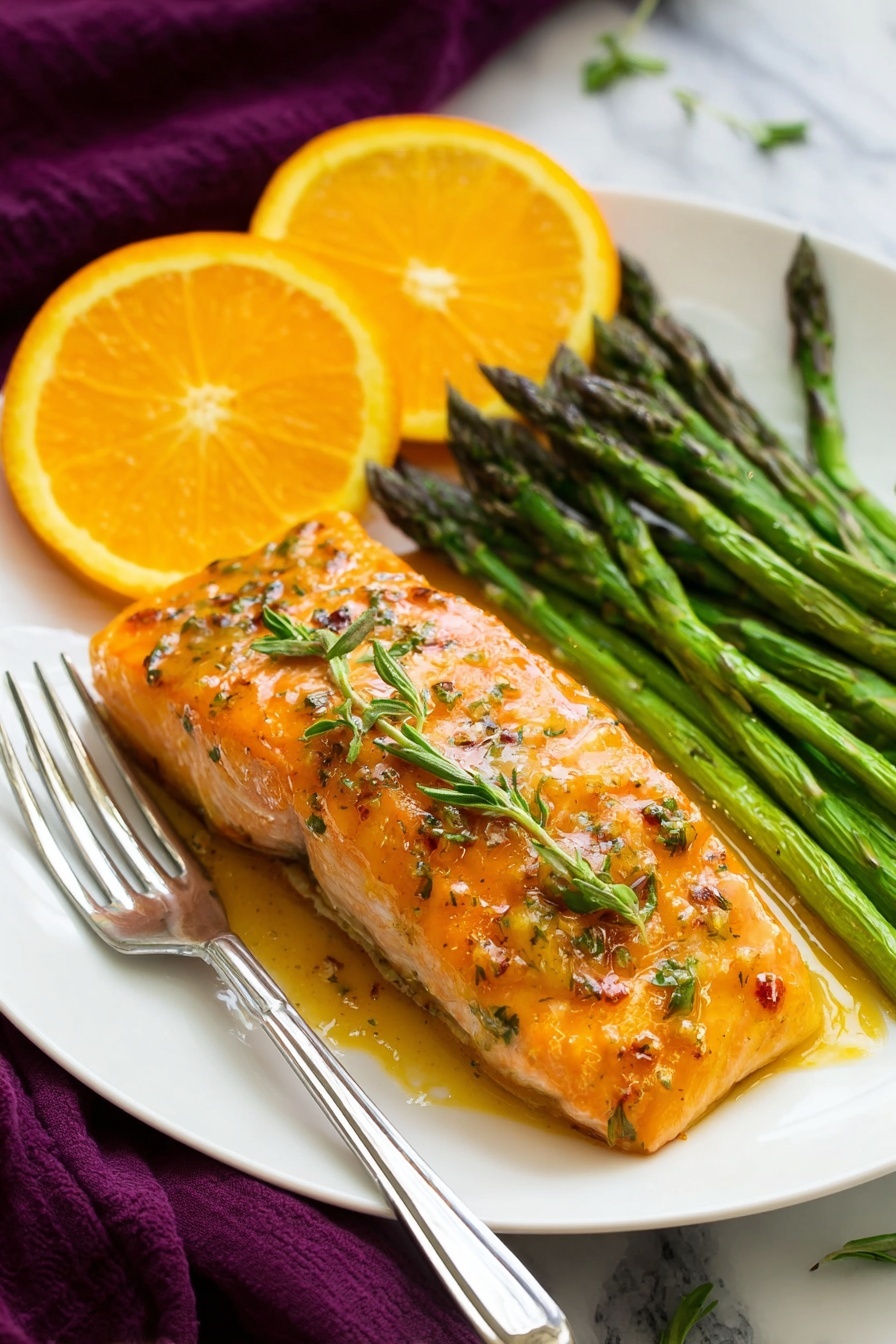 The image shows a black pan filled with four cooked salmon fillets arranged in a slightly overlapping row, each fillet golden brown and glazed with a shiny, orange-tinted sauce. Between and around the salmon pieces are thin orange slices and sprigs of fresh green rosemary, floating in the sauce. The pan sits on a white marbled surface, with a whole orange and a halved orange placed near it. A dark gray cloth is partially visible on the lower right side, and a woman's hand is holding the pan handle. photo taken with an iphone --ar 2:3 --v 7 - Orange Rosemary Glazed Salmon, citrus glazed salmon, easy healthy salmon recipe, quick salmon dinner ideas, elegant seafood dishes