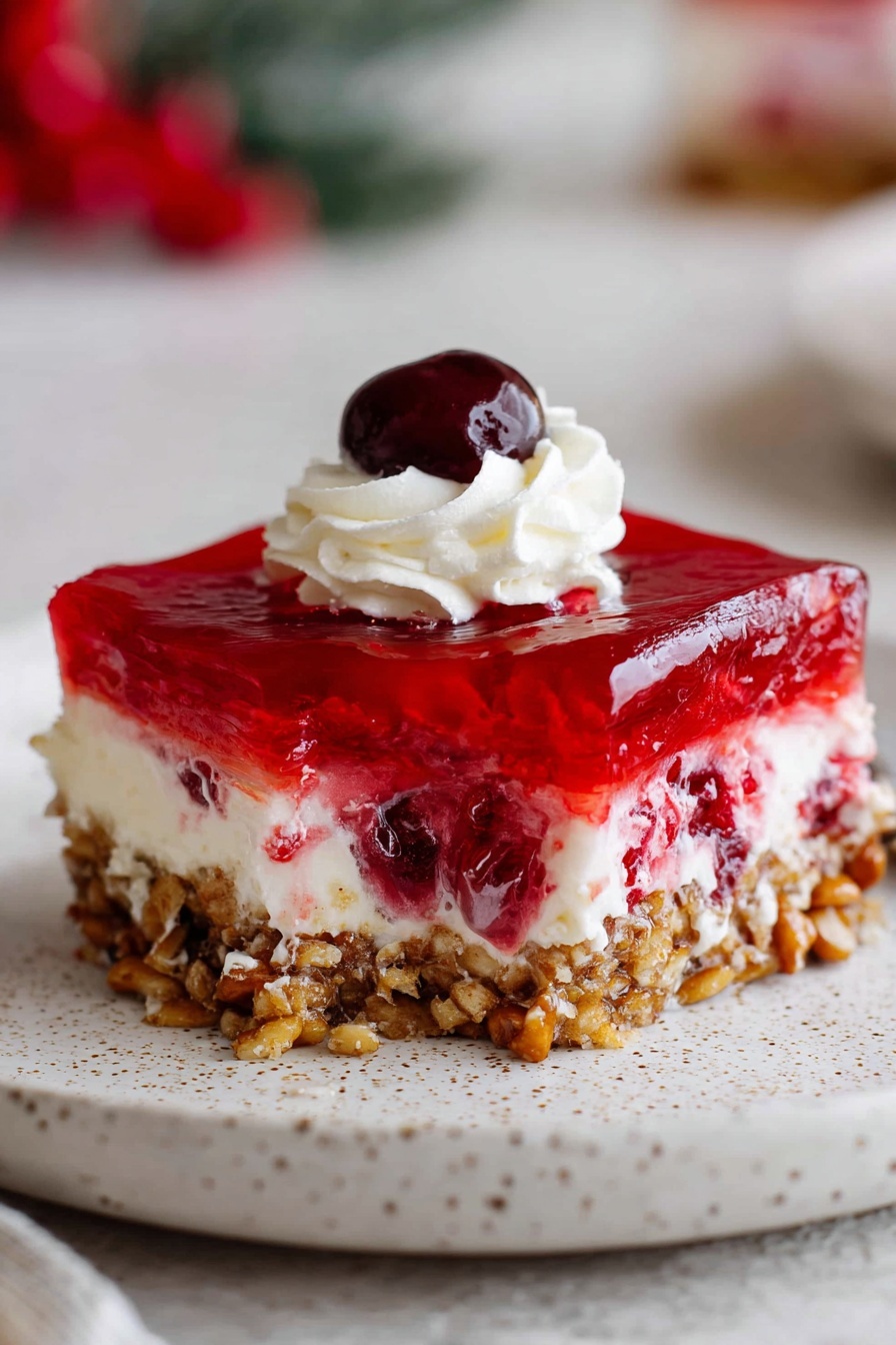 The image shows a clear glass baking dish filled with a layered dessert placed on a white marbled surface. The bottom layer is a crumbly, light brown crust with visible small pieces. Above this is a thick, creamy white layer, smooth in texture. The top layer is a shiny, deep red gelatin, spread evenly over the cream layer. On top of the red gelatin, there are six dollops of white whipped cream, piped in a swirled pattern, evenly spaced across the surface. The front left corner of the dessert has one square piece removed, showing the layers clearly. In the background, a white bowl filled with red berries is visible but out of focus. Photo taken with an iphone --ar 2:3 --v 7 - Cranberry Pretzel Salad, easy cranberry pretzel salad, holiday pretzel dessert, layered cranberry salad, salty sweet pretzel salad