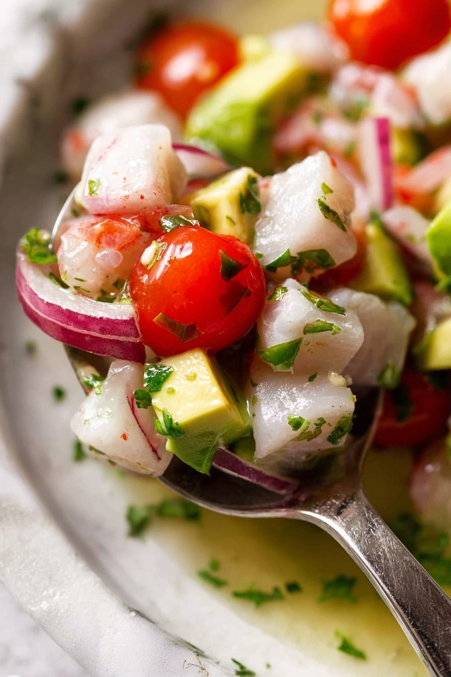 A black bowl holds a colorful ceviche mix, with three main layers: the bottom layer is light green chunks of avocado; the middle layer is white cubes of fish mixed with finely sliced red onions and chopped green herbs; the top layer is halved bright red cherry tomatoes scattered on top. On the right side of the bowl, three lime wedges lean against the ceviche, and a yellow round chip is placed standing inside the bowl next to the limes. A silver spoon lies on the left edge of the bowl, partially under the ceviche. The bowl sits on a white marbled surface, surrounded by scattered yellow round chips and a soft white cloth near the bowl. In the background, a white cup with a gray bottom holds more yellow round chips, and there are broken chip pieces and chips laying on the white marbled surface as well. Photo taken with an iphone --ar 2:3 --v 7 - Fresh Fish Ceviche, ceviche recipe, seafood appetizer, quick ceviche, citrus seafood dish