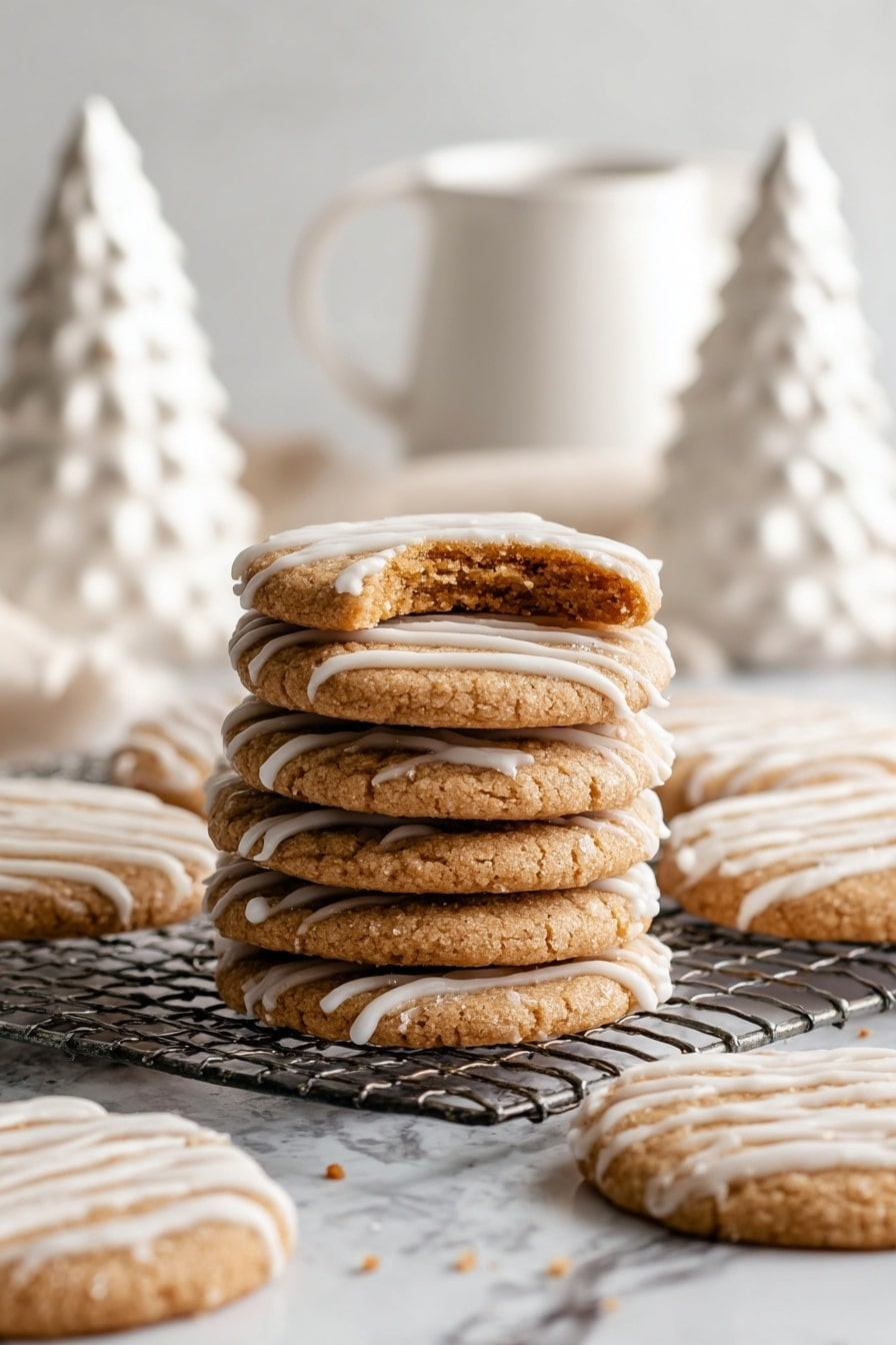 The image shows five round cookies with a light brown color and a rough, crumbly texture on top. Each cookie is drizzled with white icing in thin, uneven stripes. One cookie has a bite taken out of it, revealing a soft inside with crumbs around it. The cookies rest on crumpled white parchment paper, placed on a metal cooling rack over a white marbled surface. Small cookie crumbs and drops of icing are scattered around, adding a casual, freshly made look. Photo taken with an iphone --ar 2:3 --v 7 - Eggnog Cookies with Glaze, festive eggnog cookies, holiday cookie recipes, soft chewy cookie recipes, Christmas cookie ideas