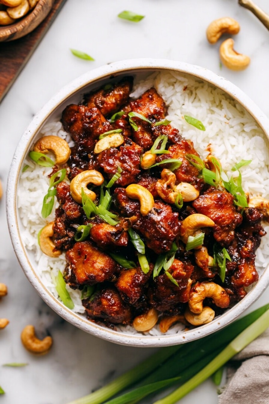 A white bowl filled with a layer of fluffy white rice at the bottom, topped with a thick layer of dark brown glazed chicken pieces mixed with whole cashew nuts. The chicken is shiny with sauce and scattered with bright green sliced spring onions, adding a fresh touch. The bowl is placed on a white marbled surface with a few cashews and spring onion pieces nearby. Photo taken with an iphone --ar 2:3 --v 7 - Slow Cooker Cashew Chicken, easy cashew chicken recipe, healthy slow cooker chicken, flavorful chicken stir-fry, simple crockpot chicken dishes