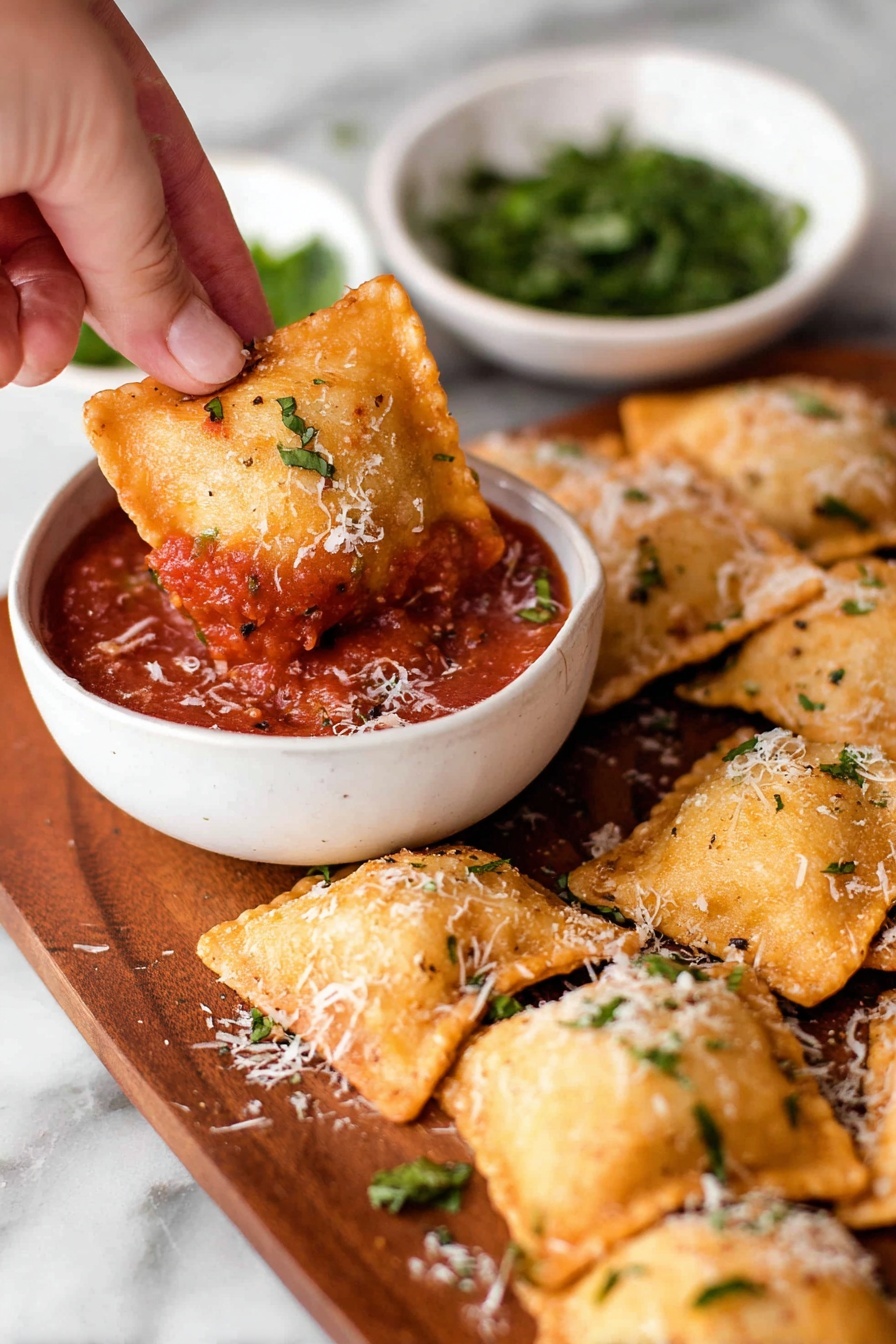 A woman's hand is holding a golden brown, crispy square ravioli, dipping it into a small white bowl filled with chunky red marinara sauce that has visible bits of herbs and spices. The raviolis are arranged on a wooden board, each showing a slightly puffed and browned texture with a light sprinkle of finely shredded white cheese and small green herb pieces scattered on top. In the background, there is another white bowl with chopped green herbs. The surface beneath is a white marbled texture. photo taken with an iphone --ar 2:3 --v 7 - Air Fryer Pizza Rolls, pizza rolls recipe, crispy pizza snack, cheesy air fryer snacks, party appetizer ideas