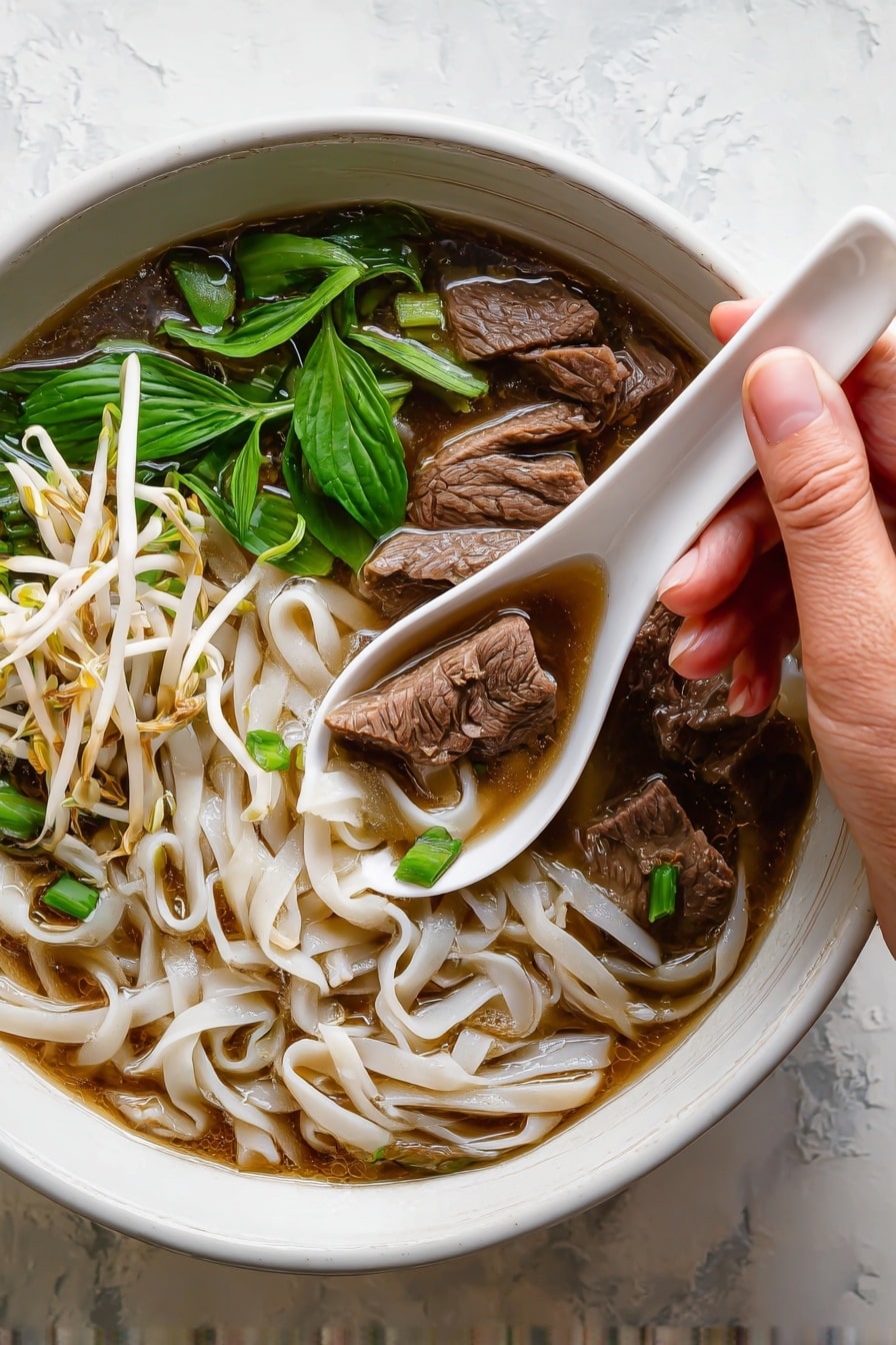 A white bowl filled with three layers: the first layer is light brown broth covering the bottom; the second layer shows white flat rice noodles spread throughout; on top there are slices of dark brown cooked beef placed in the upper right section, a bunch of fresh green basil leaves on the right side, and a heap of white bean sprouts mixed with light green cilantro leaves and two lemon wedges on the left side. The surface is a white marbled texture. Photo taken with an iphone --ar 2:3 --v 7 - Vietnamese Beef Noodle Soup, authentic Pho, homemade Vietnamese soup, beef noodle broth, Vietnamese noodle soup recipe