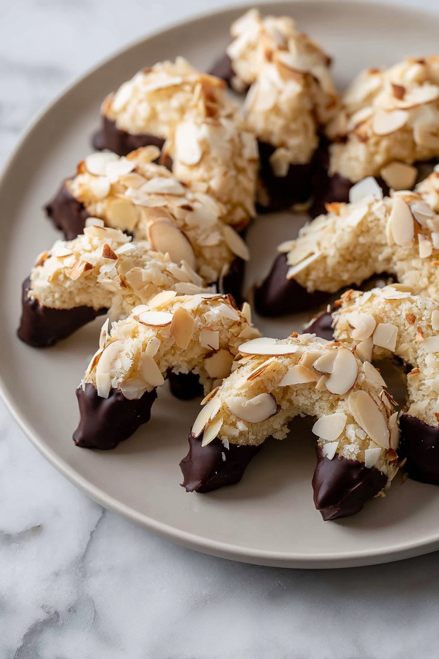 The image shows crescent-shaped cookies covered in pale cream-colored sliced almonds on the outside, placed in a single layer on a flat white plate. The ends of each cookie are dipped in dark chocolate, creating a rich dark brown contrast with the light almond flakes. The plate sits on a surface with a white marbled texture, and the cookies have a soft, crumbly texture visible beneath the almond layer. photo taken with an iphone --ar 2:3 --v 7 - Almond Horns Cookies with Chocolate Drizzle, almond cookies, chocolate drizzled cookies, nutty almond treats, elegant cookie recipes