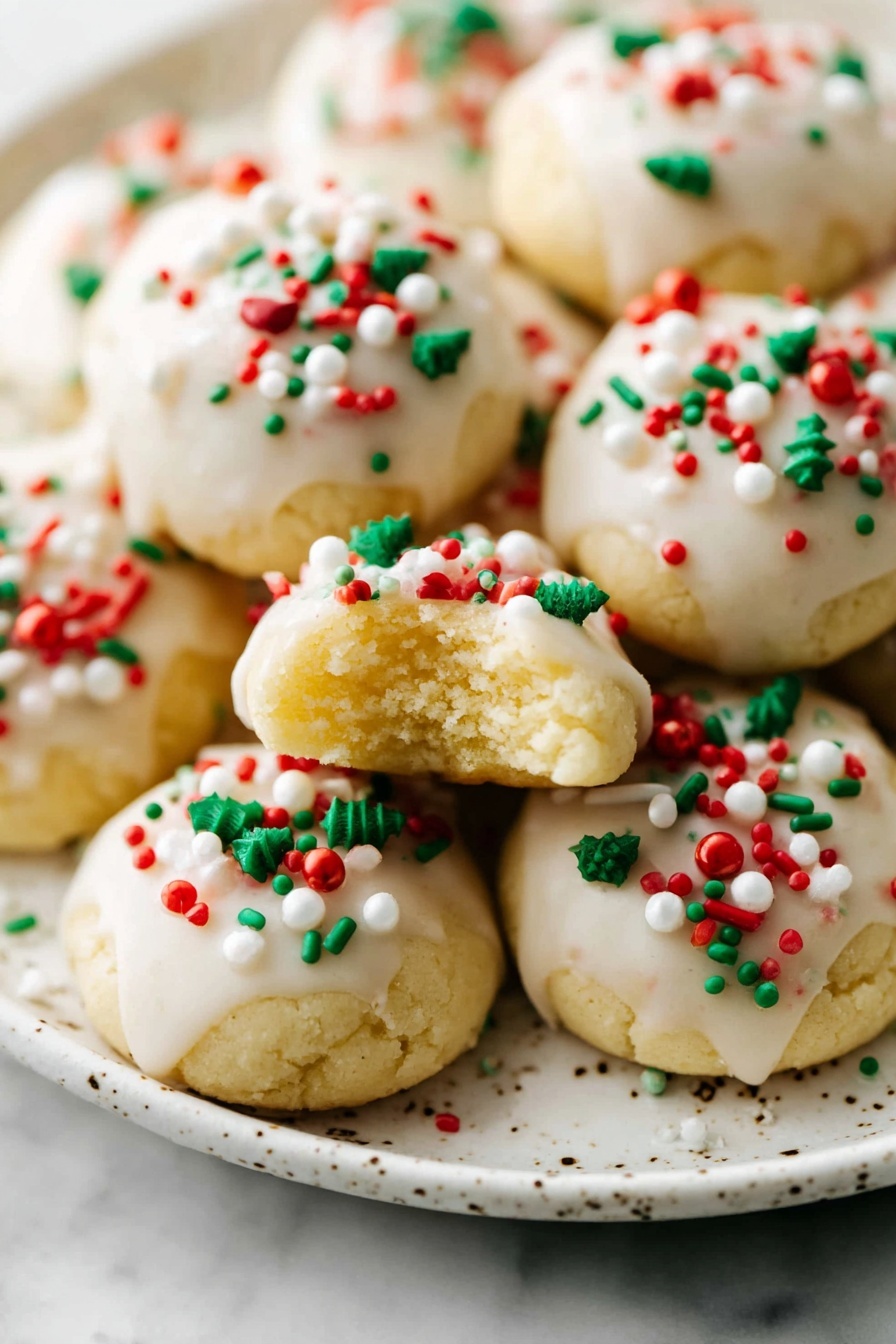 A group of soft, round cookies with a light yellow base, each topped with a smooth white icing layer that covers the entire top surface. The cookies are decorated with small round and star-shaped sprinkles in red, green, and white colors scattered unevenly on the icing. The cookies are placed closely together on a white marbled surface, creating a festive and colorful pattern. The overall look is bright and cheerful, with the different sprinkle shapes and colors adding texture and visual interest. photo taken with an iphone --ar 2:3 --v 7 - Italian Ricotta Christmas Cookies, holiday Italian cookies, soft Christmas cookies, almond glaze cookies, festive holiday cookies
