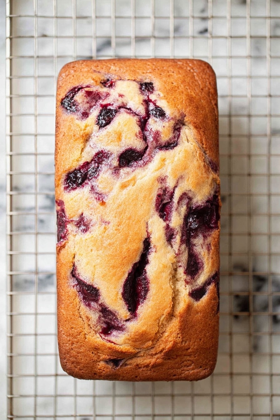 A rectangular loaf cake with a golden brown crust sits on a white marbled surface under a cooling rack. The top of the cake shows dark purple swirls of fruit filling mixed through the lighter, soft-looking batter. The swirls create an uneven marbled pattern, with some areas more concentrated with the berry color. The cake texture looks smooth with some light cracks on the surface, adding a homemade feel. photo taken with an iphone --ar 2:3 --v 7 - Cranberry Swirl Pound Cake, festive cranberry pound cake, moist cranberry pound cake, holiday cranberry dessert, easy cranberry pound cake