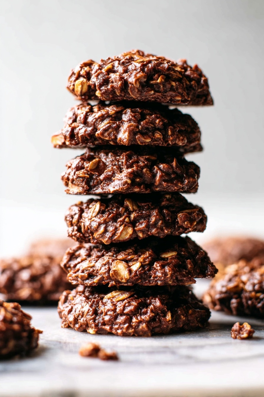 Several round chocolate oatmeal cookies are scattered on a white marbled surface. Each cookie has a rough, bumpy texture made of oats and chocolate, with a dark brown color showing different shades from smooth chocolate to lighter oat bits. The cookies are thick, firm, and evenly sized, arranged loosely with each one clearly visible. The surface beneath them is clean and light-colored, enhancing the rich color of the cookies. photo taken with an iphone --ar 2:3 --v 7 - No Bake Cocoa Peanut Butter Cookies, peanut butter chocolate cookies, no bake dessert recipes, quick no bake cookies, fudgy peanut butter treats