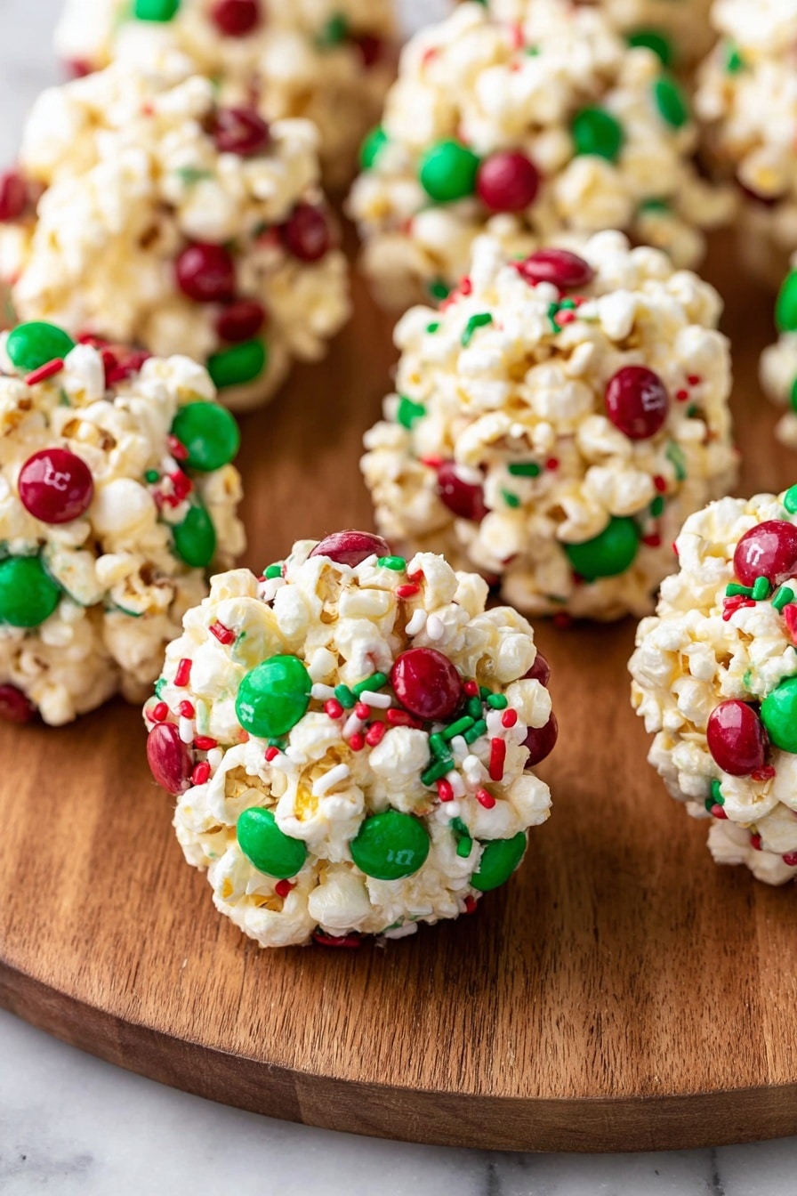 The image shows a wooden plate full of round popcorn balls. Each ball is made of white popcorn mixed tightly together, with red and green candy pieces and sprinkles spread throughout. The popcorn balls have a bumpy texture and look lightly sticky to hold their shape. The plate sits on a white marbled surface with blurred decorations around it, including green shiny Christmas ornaments, pine cones, and a white wooden block with red snowflake designs. Photo taken with an iphone --ar 2:3 --v 7 - Festive Christmas Popcorn Balls, Christmas popcorn snack, holiday treat ideas, easy holiday party snacks, festive popcorn dessert