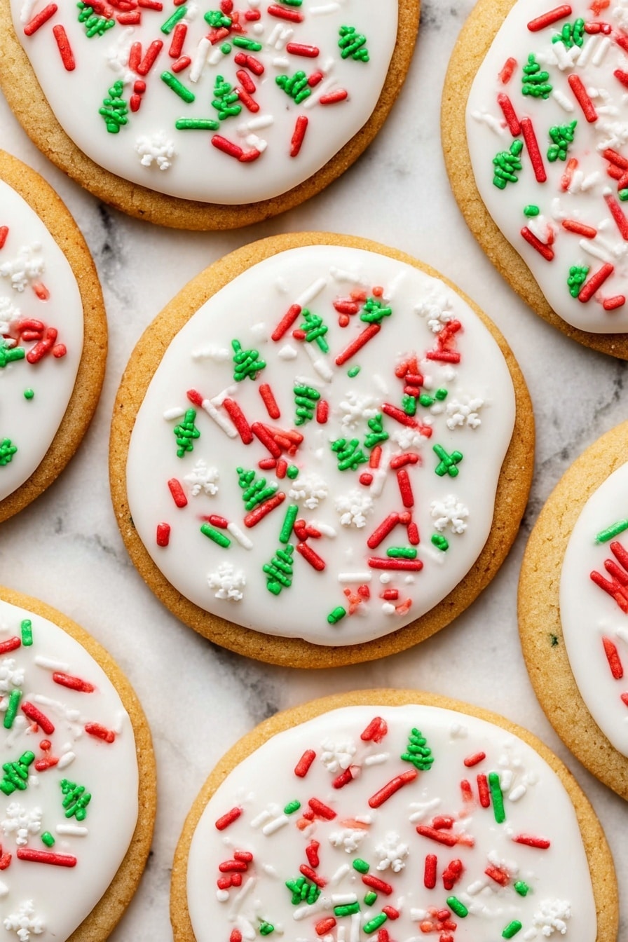 The image shows round sugar cookies with one thick golden cookie base layer visible. On top of each cookie is a smooth, thick layer of white icing spread evenly. The icing is decorated with small colorful sprinkles in red, green, and white shapes including candy canes, snowflakes, and Christmas trees scattered over the surface. One cookie in the middle has a bite taken out of it, showing the soft texture of the cookie inside. The cookies are placed on a white marbled surface. photo taken with an iphone --ar 2:3 --v 7 - Christmas Shortbread Cookies, holiday butter cookies, festive shortbread, easy Christmas cookies, melt-in-your-mouth holiday treats