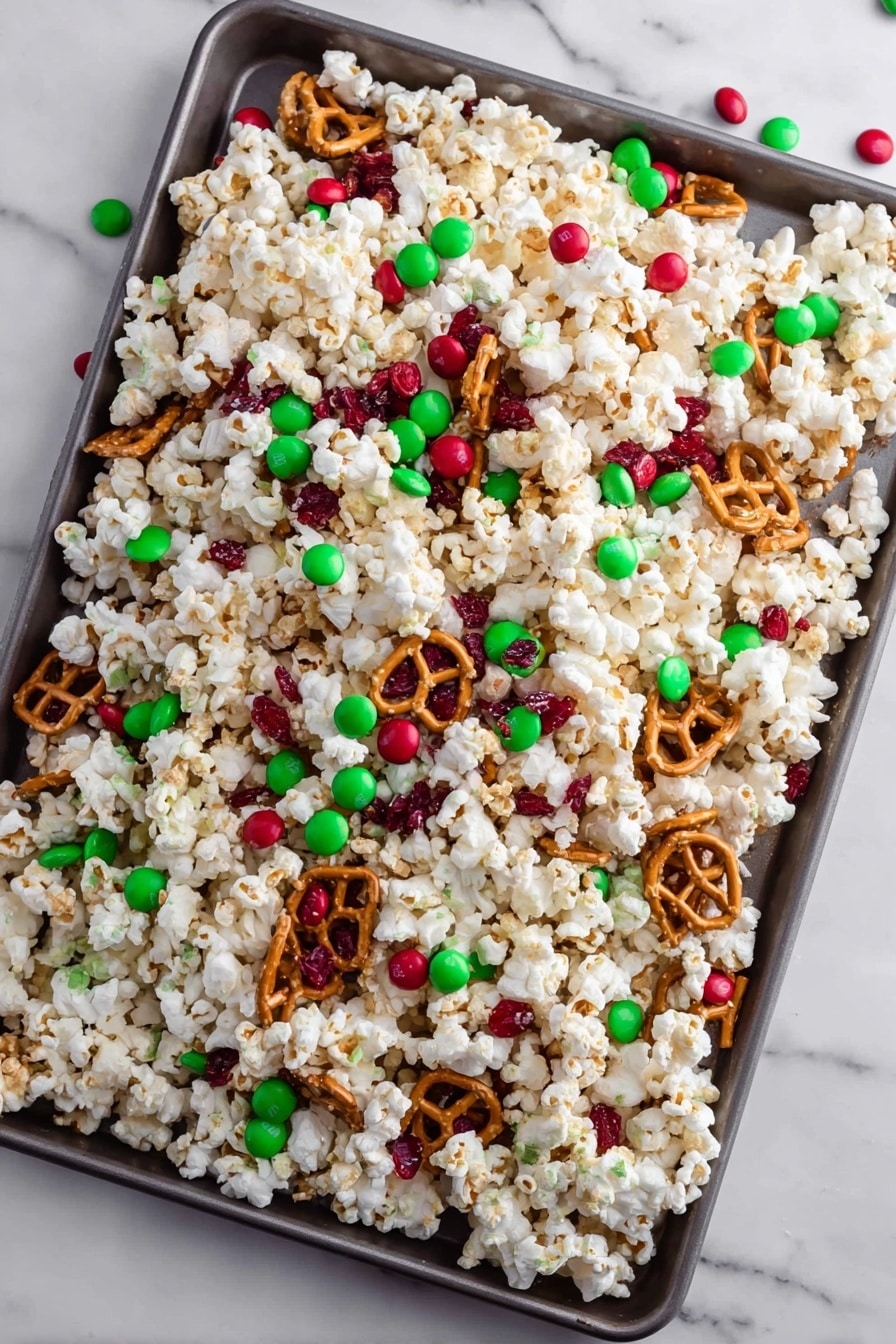 A large baking tray filled with a mix of white popcorn, twisted golden brown pretzels, and scattered red and green candy-coated chocolates that add bright pops of color throughout. The popcorn forms the main white, fluffy base layer, with pretzels popping up here and there while the candies sit on top and inside the mix. The tray is placed on a white marbled surface, with one piece of popcorn floating above as if falling. photo taken with an iphone --ar 2:3 --v 7 - Festive Christmas Popcorn Snack, Christmas popcorn mix, holiday holiday snack, Christmas party treat, easy Christmas snacks