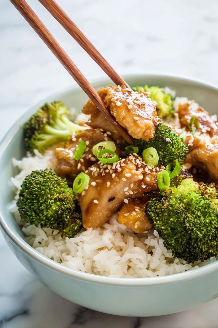A close-up of a spoon holding pieces of glazed brown chicken and green broccoli florets, lifted above a bowl filled with two layers, the first layer being white rice with a fluffy texture, and the second layer showing some sauce mixing into the rice; the bowl is white with a light green rim and sits on a white marbled surface. In the background, there are blurred items including a white rice cooker and a bowl with green garnish. Photo taken with an iphone --ar 2:3 --v 7 - Crockpot Broccoli Chicken, slow cooker chicken and broccoli, easy healthy crockpot dinner, flavorful slow cooker chicken recipes, effortless crockpot chicken dish