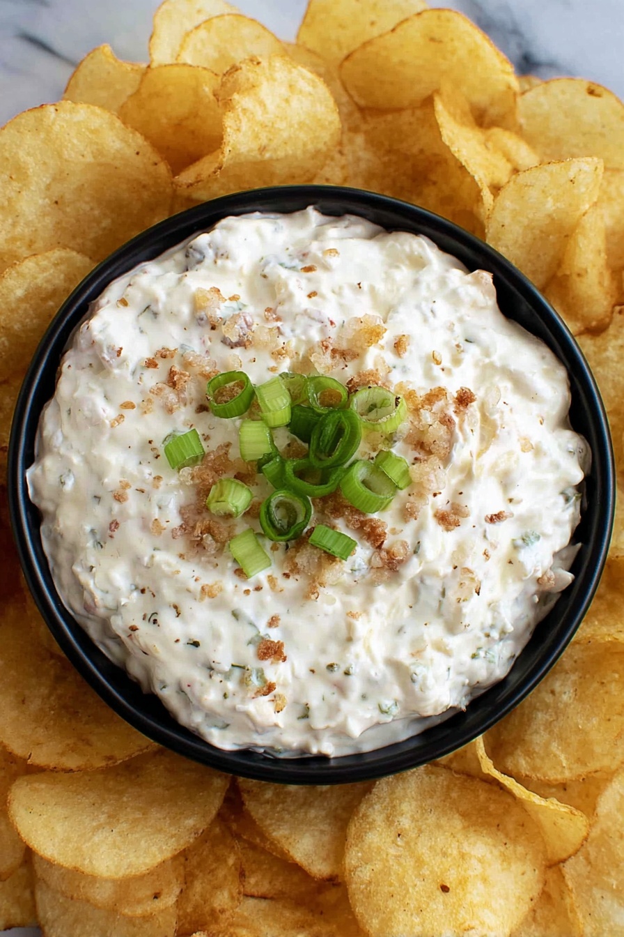 The image shows a black bowl filled with thick white dip mixed with small bits of beige and light brown, giving the dip a textured look. On top, finely chopped green onions are scattered, adding a fresh green color contrast. The bowl sits on a white marbled surface, and around it, there are light beige rolled tortilla chips partly visible. The lighting highlights the creamy texture of the dip and the brightness of the green onions. Photo taken with an iphone --ar 2:3 --v 7 - Cream Cheese Clam Dip, seafood dip with cream cheese, easy clam dip recipe, savory seafood appetizer, quick clam dip