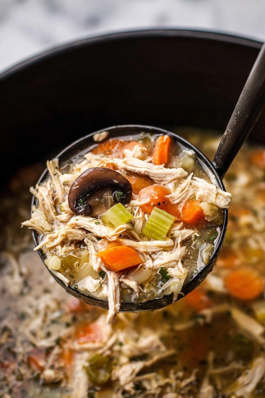 A white bowl filled with clear broth soup containing shredded light brown chicken, bright orange carrot slices, dark brown mushroom pieces, and light green celery chunks. A wooden spoon with a smooth texture is partly submerged in the soup on the right side of the bowl. The bowl sits on a white marbled surface, and there is a white cloth with blue stripes on the right edge of the image. A second bowl with similar soup is blurry in the background on the left side. Photo taken with an iphone --ar 2:3 --v 7 - Slow Cooker Turkey and Rice Soup, turkey and rice soup, easy slow cooker soup, healthy turkey soup, hearty rice soup
